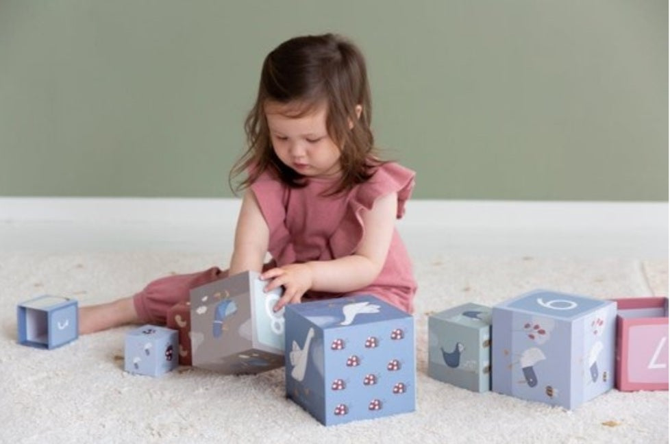 Kind speelt op de grond met de stapelblokken in verschillende kleuren en formaten.